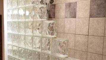 A bathroom with a glass block partition, a shower area, and tiled walls.