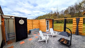 A wooden outdoor patio with Adirondack chairs, a wood stove, and a door labeled 'PORCH.'