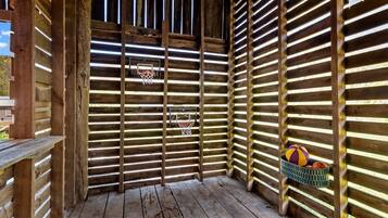 A wooden structure with a basketball hoop and a basket of balls.