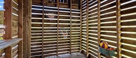 A wooden structure with a basketball hoop and a basket of balls.