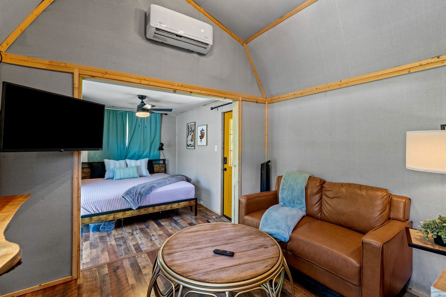 A compact room with a bed, a sofa, a small table, and a television.