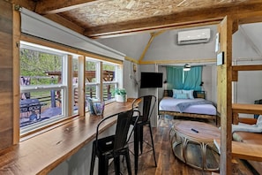 Una stanza compatta con una scrivania in legno, un letto, una TV e una finestra che dà su un patio.
