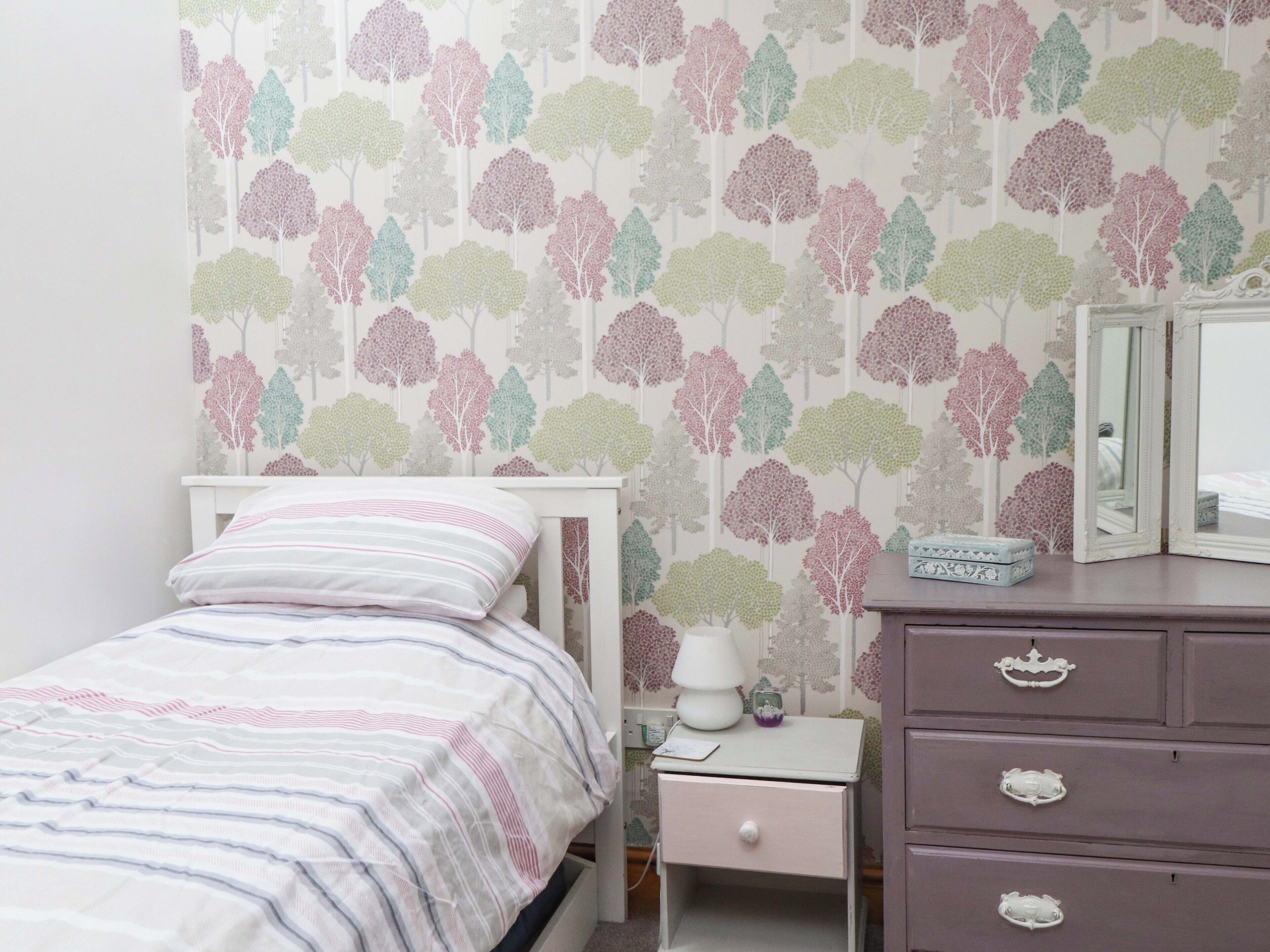 Un dormitorio con cama, mesita de noche, cómoda y espejo.