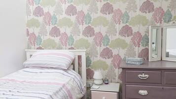 Un dormitorio con cama, mesita de noche, cómoda y espejo.