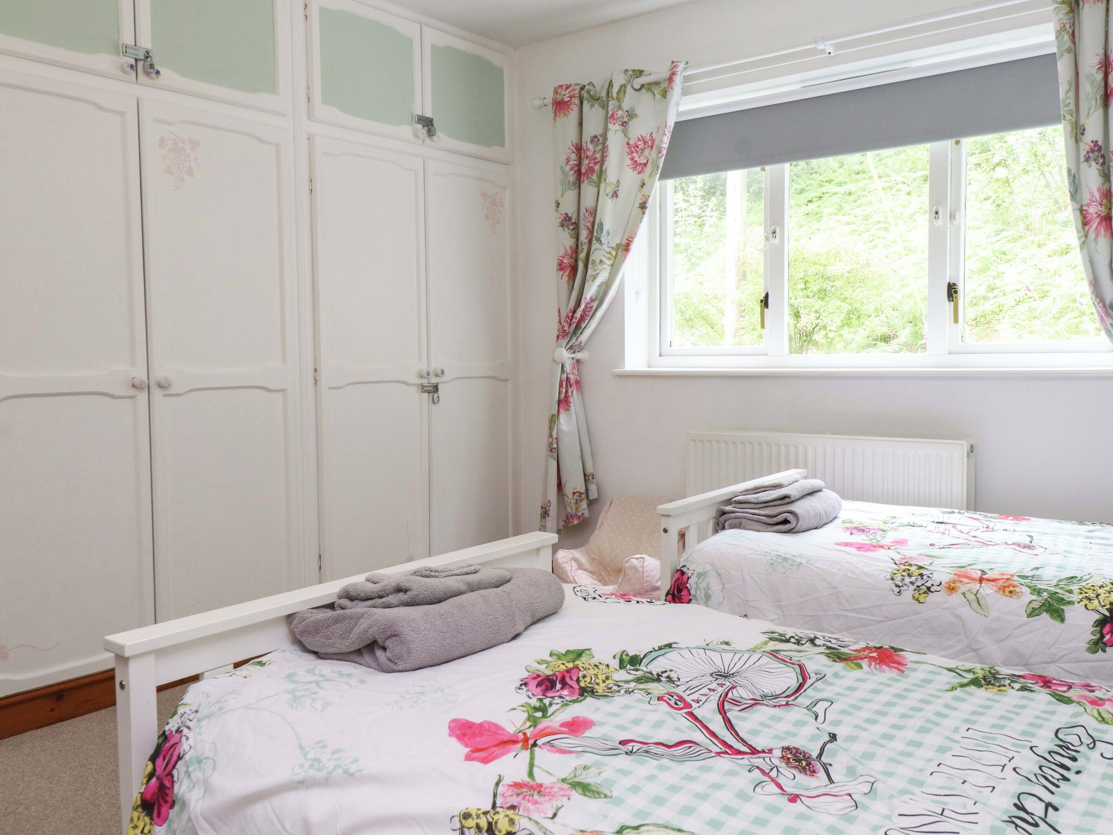 Un dormitorio con dos camas, una ventana con cortinas, un radiador y un armario.