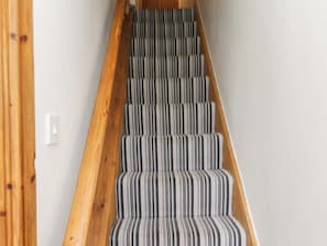A staircase with wooden handrails and striped carpeted steps.