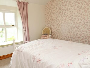 A bedroom with a bed, a window with curtains, and floral wallpaper. - 2 Bryn Eglwys (Porthmadog)