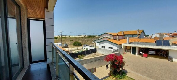 A residential area with a balcony, a building with a tiled roof, and a clear sky. - Casa do Mar (COSTA NOVA)