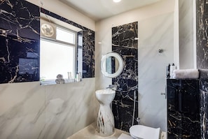 A bathroom with a marble sink, a toilet, a mirror, and a shower. - Alaya Stays Gold Palm Resort (Amer)
