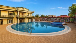 Una gran piscina exterior amb un pont de fusta, un edifici amb balcons, i una paret colorida al fons.