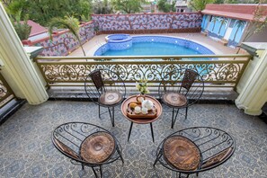 Un balcó amb una piscina, quatre cadires i una taula amb una safata de teieres i tasses.