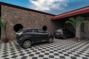 A building with a stone facade, two vehicles parked in front, and a checkered floor. - Alaya Stays Gold Palm Resort (Amer)