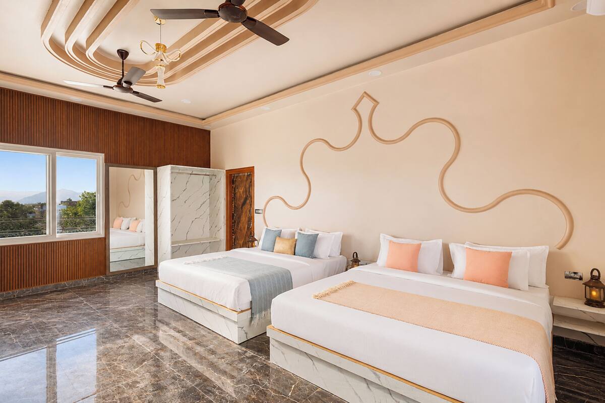 Una habitación de hotel con dos camas, ventilador de techo, un ventanal grande y suelo de mármol.