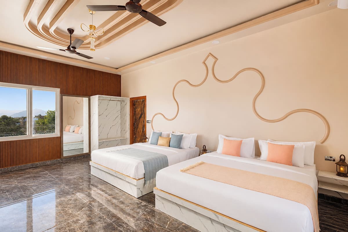 A hotel room with two beds, a ceiling fan, a large window, and a marble floor.