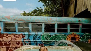 Una persona relajándose en un jacuzzi con un mural colorido al fondo.