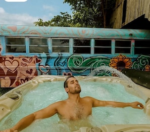 A person relaxing in a hot tub with a colorful mural in the background.