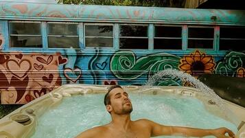 A person relaxing in a hot tub with a colorful mural in the background.