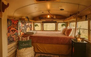 Un ambiente accogliente con un letto, un cuscino con la scritta 'love', un tavolino con una candela e un affresco sulla parete.