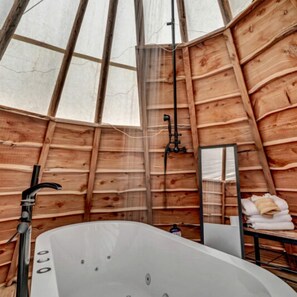 Puinen sisustus, jossa on suuri kylpyamme, peili ja pyyhkeet.