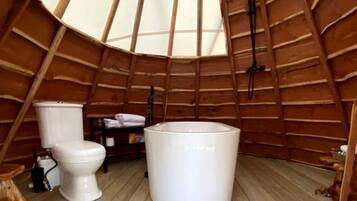 A wooden interior with a toilet, a bathtub, and a wooden floor.