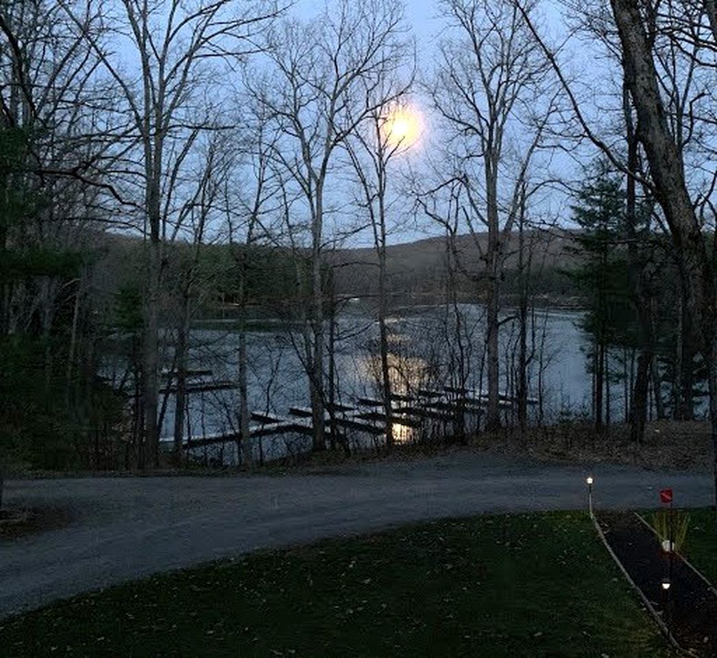 Une vue sur le lac, avec un quai en bois, des arbres et un sentier menant à l’eau.