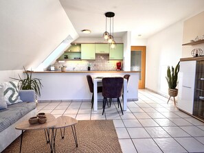 Cozinha moderna com área de jantar, sofá e máquina de café.