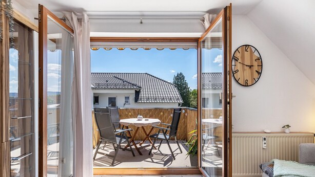 Huoneessa on liukuovilla varustettu lasiterassi, joka johtaa parvekkeelle, jossa on pöytä ja tuolit. Seinällä on kello ja huoneessa on myös patteri.