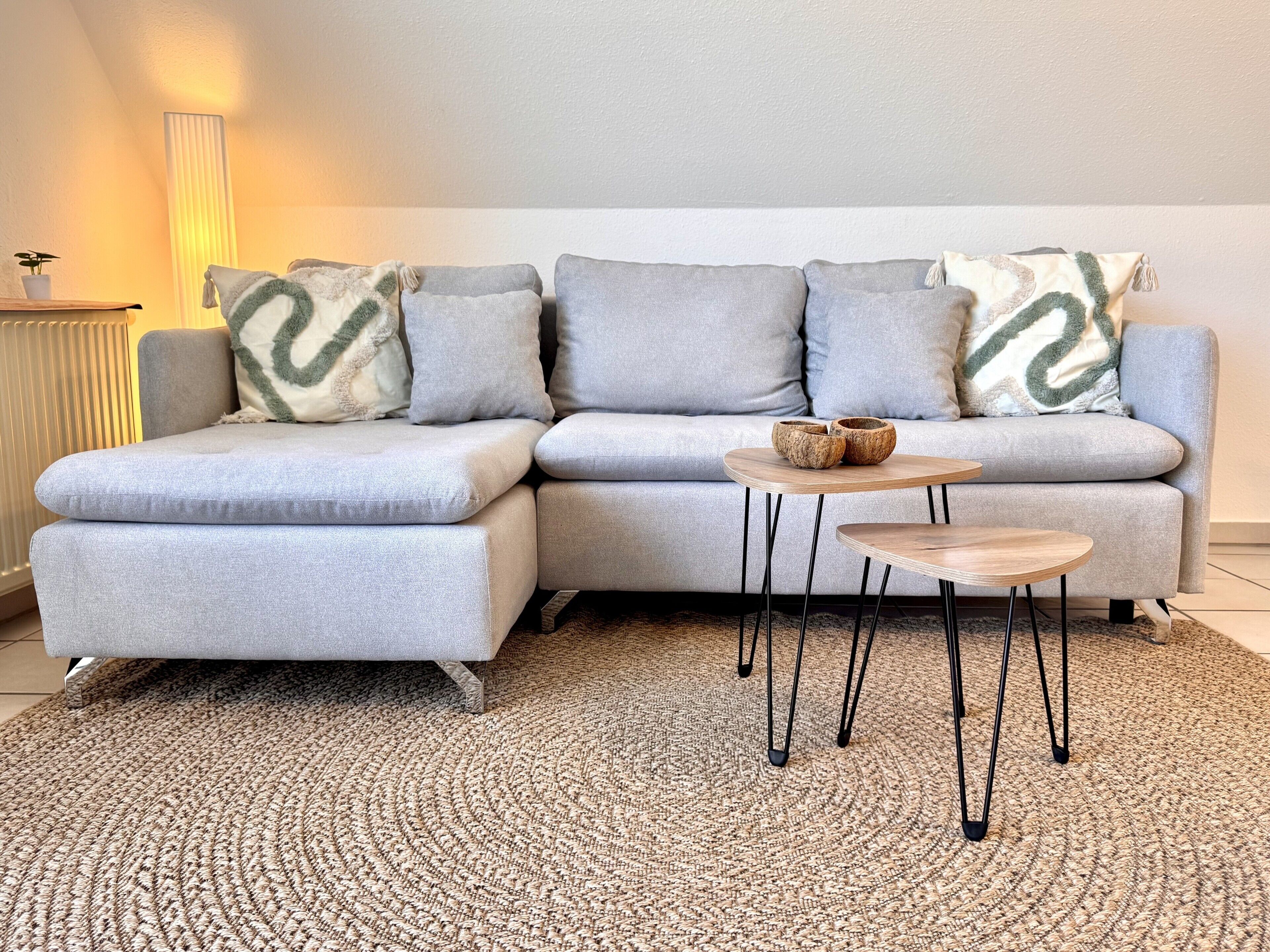 A sectional sofa with a woven rug and two small tables.. Premium Lake Loft 2-Room Apartment on Lake Constance, Dog Included, Long Stays Welcome