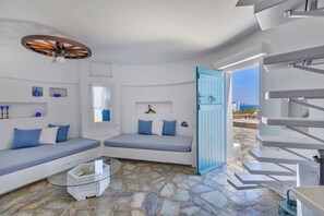 Ein Zimmer mit Steinboden, einer blauen Tür, einem weißen Sofa und einem Glastisch.