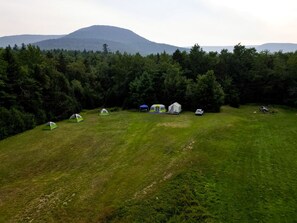 A campsite with tents and a car, surrounded by trees and a mountain in the background. - Secluded Glamping Tent with Trout Stream Near Great Northern Catskills in Elka Park, New York (Elka Park)