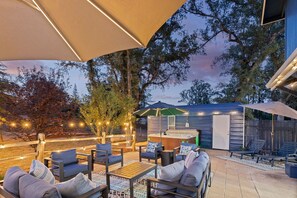Eine Terrasse im Freien mit Sitzgelegenheiten, einem Whirlpool und einem kleinen Gebäude, vermutlich eine Sauna oder ein Dampfbad.