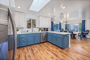 Una cocina moderna con armarios azules, un tragaluz y un comedor con vistas.