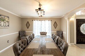 A dining room with a long wooden table, cushioned chairs, decorative wall art, and a chandelier. - Modern Villa with Sauna, Pool & Panoramic Views in Bushkill, Pennsylvania (Bushkill)