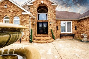A brick house with a large arched entrance, a stone fountain, and a well-maintained lawn. - Modern Villa with Sauna, Pool & Panoramic Views in Bushkill, Pennsylvania (Bushkill)