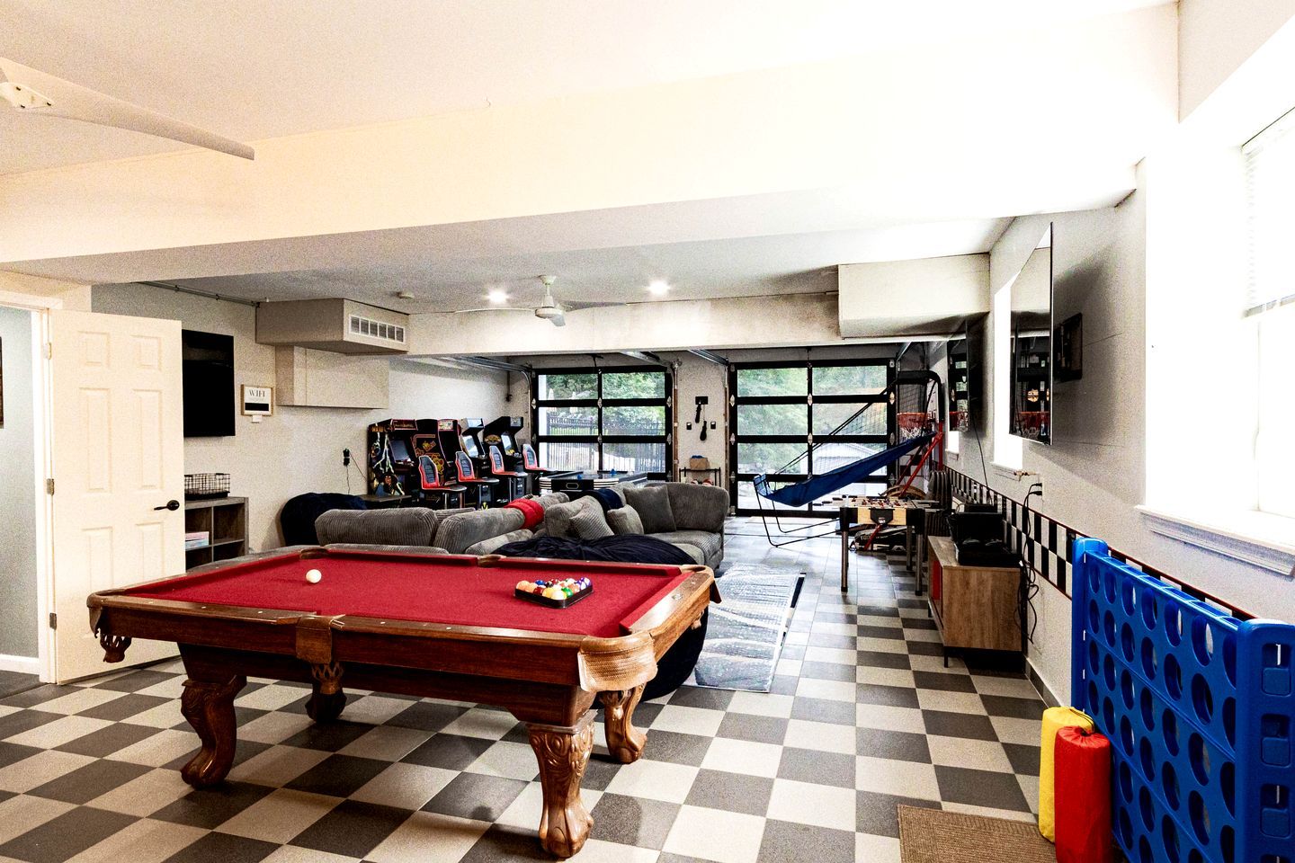 A pool table, a sofa, a hammock, and a view of the outdoors.