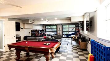 A pool table, a sofa, a hammock, and a view of the outdoors.