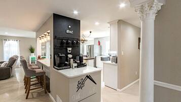 Une cuisine moderne équipée d’un coin café, d’un espace repas avec des chaises et d’un salon avec un canapé.