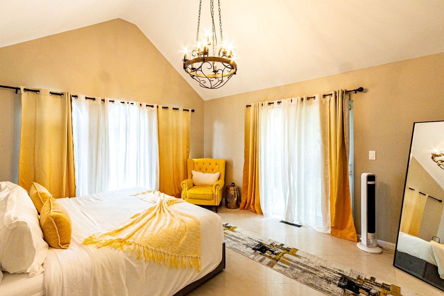 Une chambre à coucher avec un lit, une chaise, un miroir et un lustre.