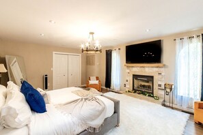 A bedroom with a bed, a TV, a fireplace, and a large mirror. - Modern Villa with Sauna, Pool & Panoramic Views in Bushkill, Pennsylvania (Bushkill)