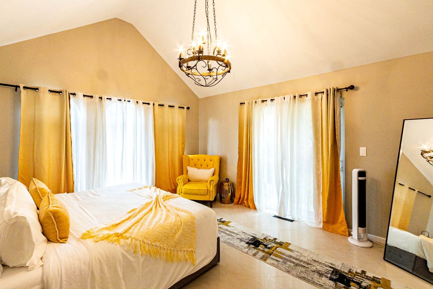 Une chambre à coucher avec un lit, une chaise, un miroir et un lustre.