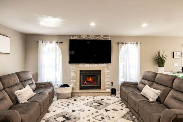 A living room with two sofas, a fireplace, and a flat-screen TV.