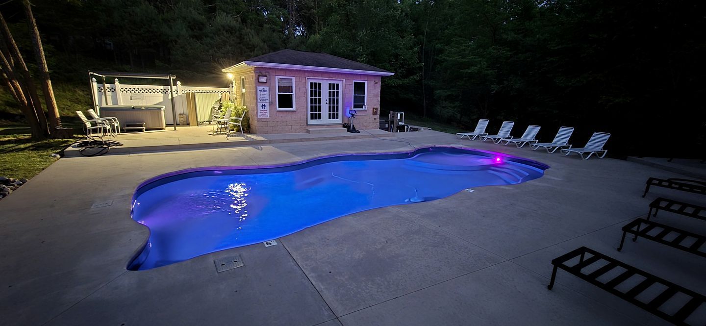 A swimming pool with lounge chairs and a small building with a door and windows.