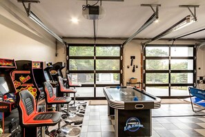 A room with arcade games, a pool table, and large windows.