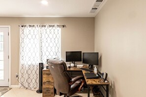 A home office with a desk, two monitors, a keyboard, and a chair.