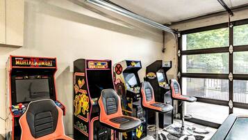 Une rangée de bornes d’arcade avec des sièges, un sol carrelé et une porte de garage avec des fenêtres.