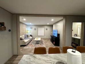 Een woonkamer met een bank, televisie en een eethoek.