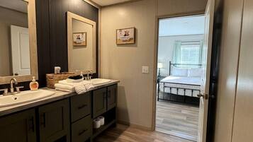 A bathroom with two sinks, a large mirror, and a wooden floor.