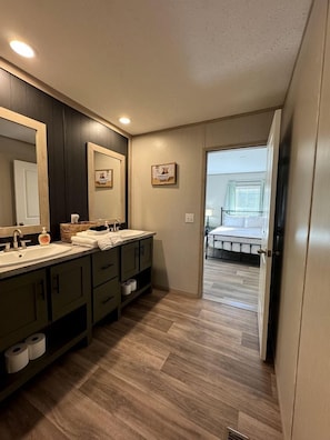 Une salle de bain avec deux lavabos, un grand miroir et un plancher en bois.
