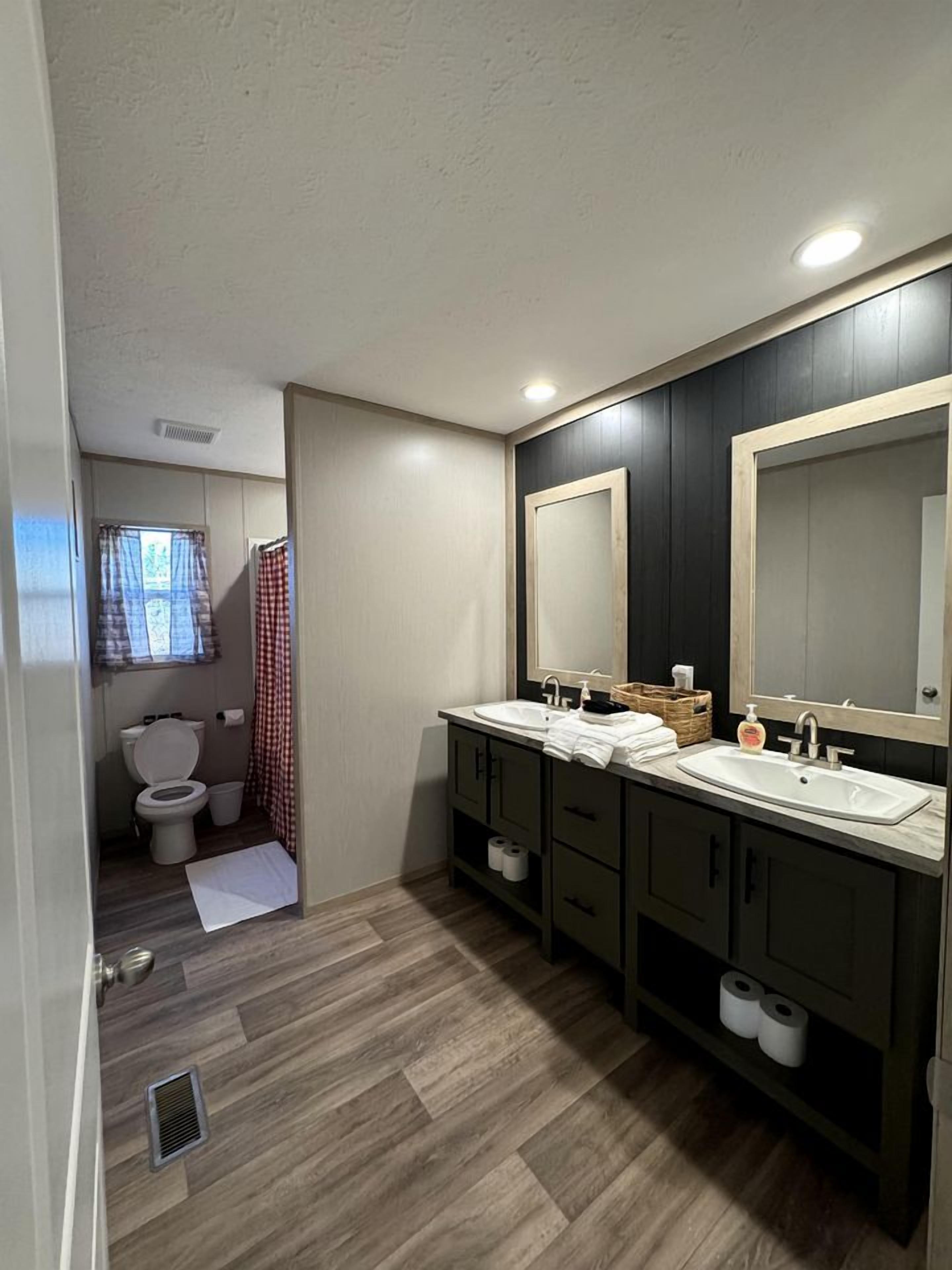 Un baño compacto con inodoro, bidé, dos lavamanos y un espejo grande.