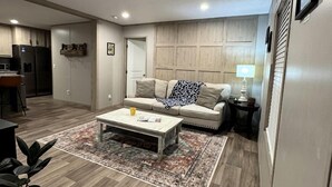 Een moderne woonkamer met een bank, salontafel en vloerkleed.